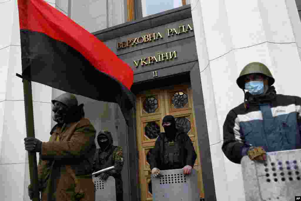 Anti-government protesters stand guard in front of the Ukrainian parliament in Kyiv. Protesters took control of the capital and parliament and sought to oust the president.