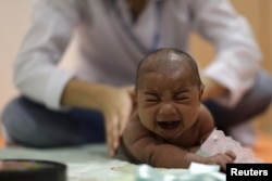 FILE - Pietro Rafael, who has microcephaly, reacts to stimulus during an evaluation session with a physiotherapist at the Altino Ventura rehabilitation center in Recife, Brazil, Jan. 28, 2016.
