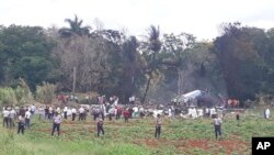 Rescue and search workers on the site where a Cuban airliner with 104 passengers on board plummeted into a yuca field just after takeoff from the international airport in Havana, Cuba, Friday, May 18, 2018. (AP Photo/Andrea Rodriguez)