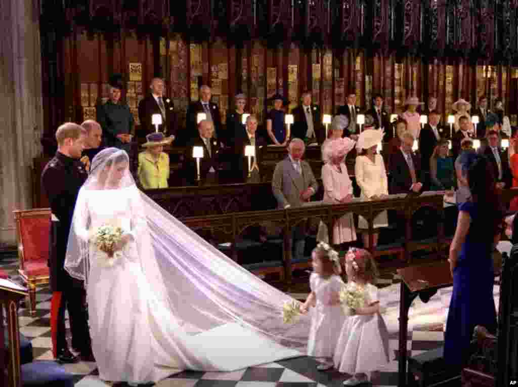 Vestido sencillo que sorprendió a medio mundo. Seda blanca con manga francesa, cola y escote barco, para no distraer la atención de la novia. Para algunos los "cortes simples y siluetas ajustadas" son habituales en el vestuario de Markle.