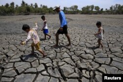 A father with his children walk over the cracked soil of a 1.5 hectare dried up fishery at the Novaleta town in Cavite province, south of Manila May 26, 2015. President Benigno Aquino III approved the proposal of the National Food Authority (NFA) to impor