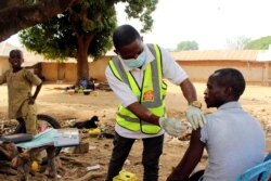 Yunusa Bawa, a community health worker, injects a man with AstraZeneca coronavirus vaccine in Sabon Kuje on the outskirts of Abuja, Nigeria, Dec 6, 2021.