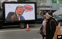 FILE - Protesting tech workers walk past a mobile billboard of Donald Trump in San Francisco, California, Feb. 13, 2017.