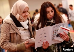 Two women visit the second job fair for migrants and refugees in Berlin, Germany, Jan. 25, 2017.