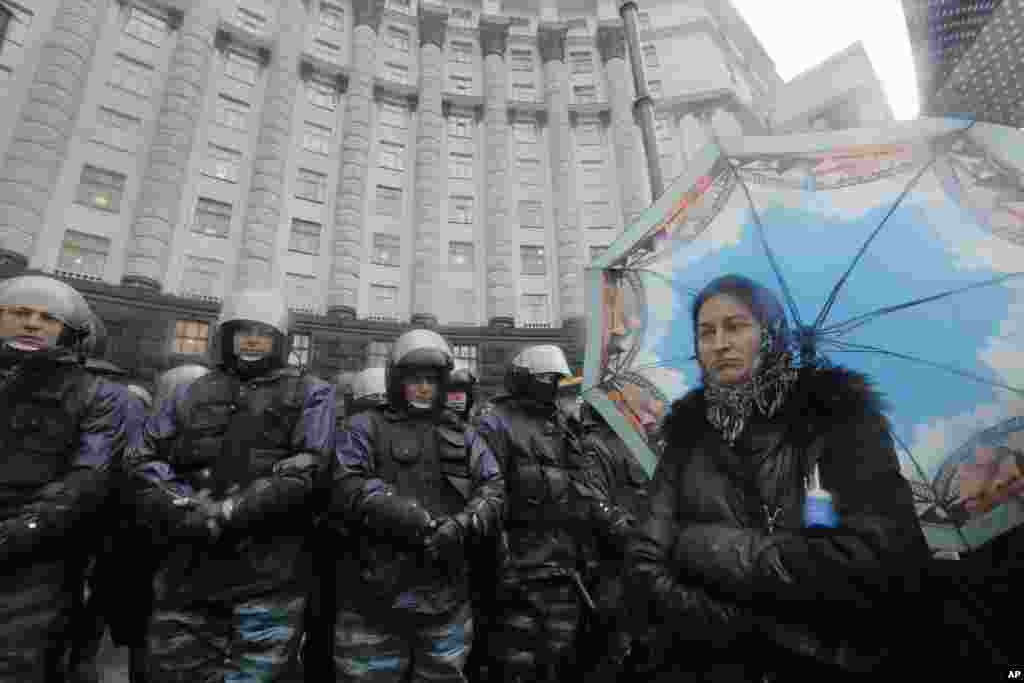 A female opposition supporter stands near to riot police during a protest in front of the Ukrainian Cabinet of Ministers in Kyiv, Nov. 25, 2013. 
