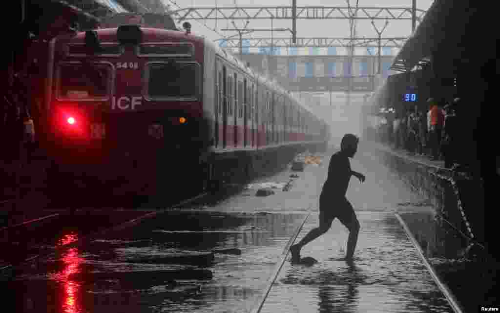 ممبئی میں ایک راہ گیر زیرِ آب ریلوے لائن سے گزر رہا ہے۔ ممبئی میں بارشوں سے ریلوے کا نظام بھی بری طرح متاثر ہوا ہے۔