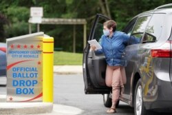 A woman wearing a mask to prevent the spread of coronavirus disease (COVID-19) casts her ballot for Maryland's primary election at a drop box in Rockville, Maryland, U.S., June 2, 2020. REUTERS/Kevin Lamarque