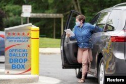 A woman wearing a mask to prevent the spread of coronavirus disease (COVID-19) casts her ballot for Maryland's primary election at a drop box in Rockville, Maryland, U.S., June 2, 2020. REUTERS/Kevin Lamarque