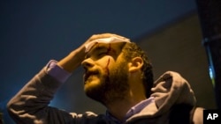 Matt Pearce, a reporter with the Los Angeles Times, holds his head after getting hit by a rock thrown into the crowd during a protest in the streets against the August shooting of Michael Brown, Sunday, Nov. 23, 2014, in St. Louis. Ferguson and the St. Lo