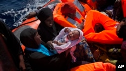 Une femme porte son bébé dans un canot transportant des migrantes venues du Nigeria secourues sur la Méditerranée, à environ 17 miles au nord de Sabratha, Libye, 28 août 2016. 