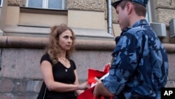 Russian activist of the feminist protest group Pussy Riot Maria Alekhina talks to a policeman as she holds a protest in front of the Federal Penitentiary building in Moscow, Russia, Aug. 7, 2018. 