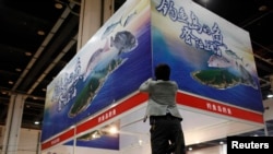 FILE - A vendor installs a poster above his booth, which sells fishes caught by Zhejiang fishermen in waters near disputed islands, known as Diaoyu in China and Senkaku in Japan, during a food exhibition in Shanghai.