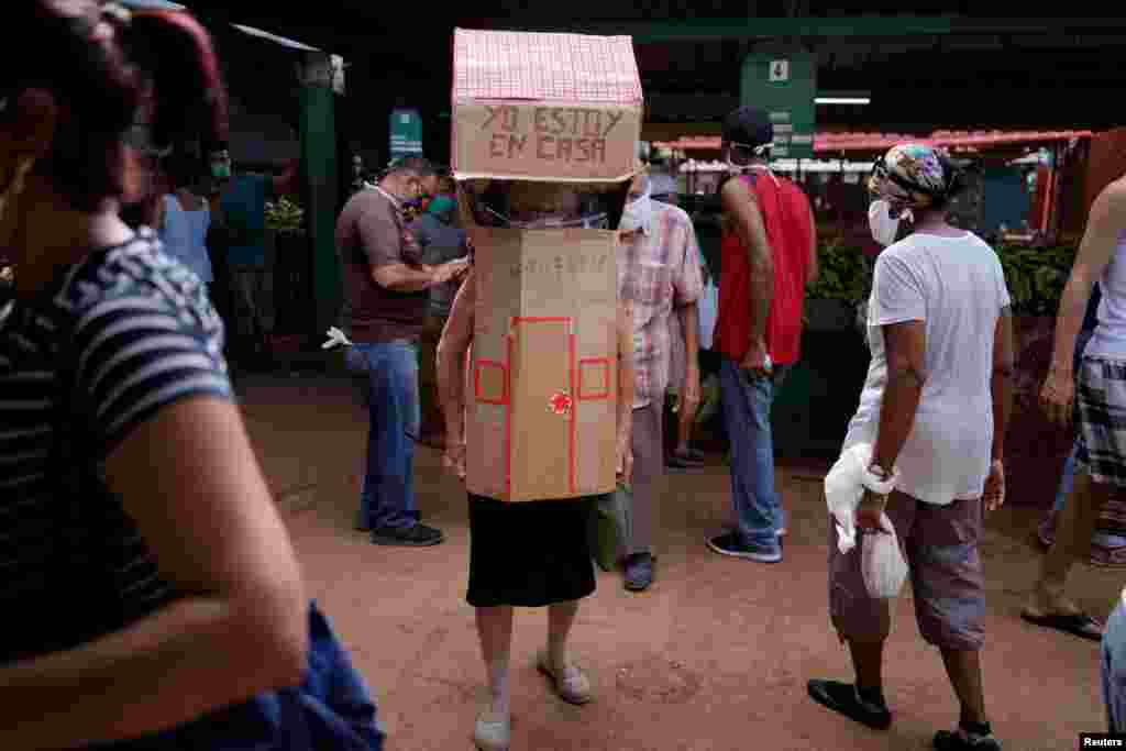 Retired nurse Feridia Rojas, 82, wears cardboard shaped in a house at a market to protect herself from the spread of the coronavirus outbreak, in Havana, Cuba.