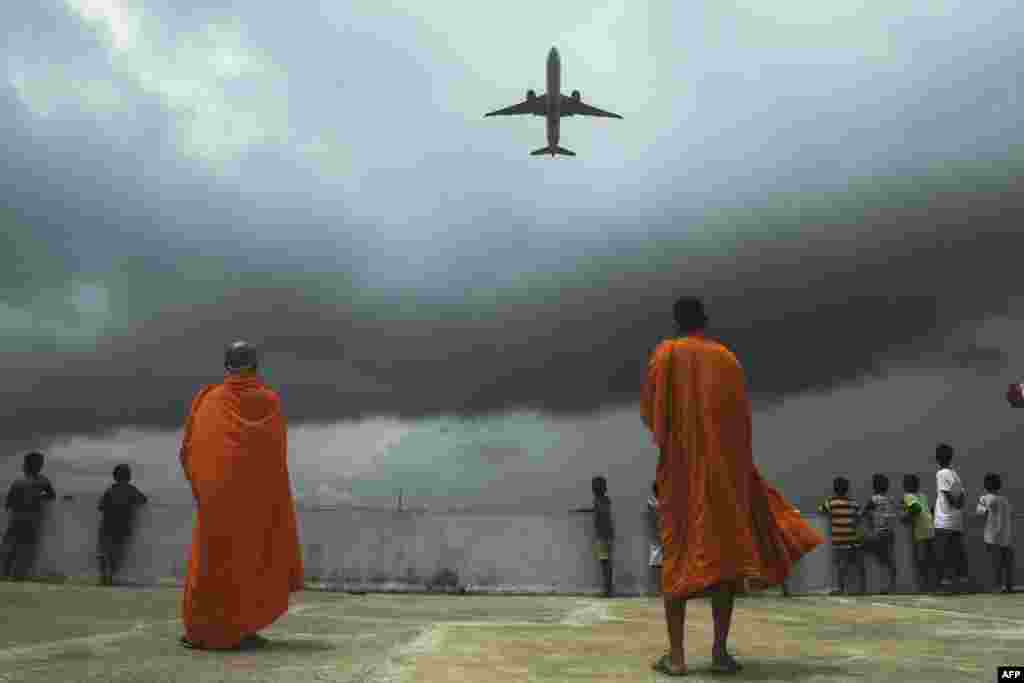 Buddhists monks and children look at an international passenger flight taking off at the Netaji Subhash Chandra Bose International Airport, from the rooftop at a Buddhist mission hostel and school for underprivileged children in&nbsp;in Kolkata, India.