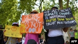 Protesters hold up placards as they gather for a march calling for action to combat climate change organised by the climate campaign group Mothers Rise Up in central London on May 12, 2019. - People took to the streets in the British captial on May 12 – I