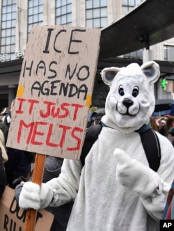 A protestor wearing a polar bear suit holds a placard during a demonstration against climate change in Brussels, Thursday, Jan. 17, 2019. (AP Photo/Geert Vanden Wijngaert)