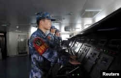 FILE - Chinese naval soldiers are pictured manning their stations on China's first aircraft carrier Liaoning, as it travels towards a military base in Sanya, Hainan province.