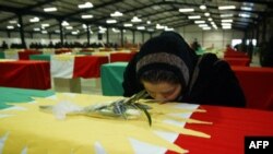 A Kurdish Iraqi woman kisses the coffin of a loved one