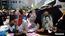 FILE - Women hold portraits of deceased former South Korean "comfort women" during a weekly anti-Japan rally in Seoul, South Korea, Aug. 15, 2018.