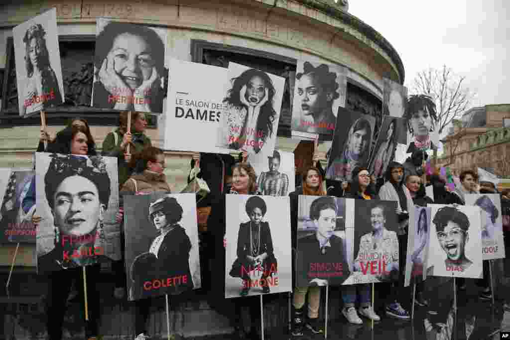 Women hold posters of famous feminists during a gathering to mark International Women&#39;s Day in Paris, France.