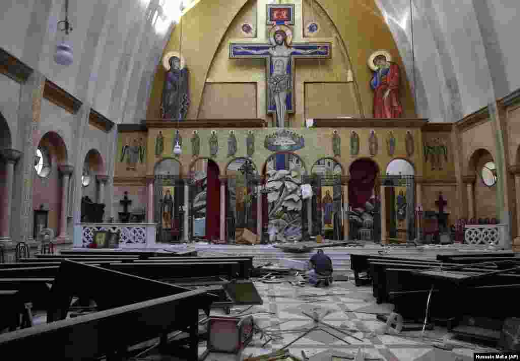 Чоловік підіймає ікони з підлоги пошкодженої церкви. 5 серпня.