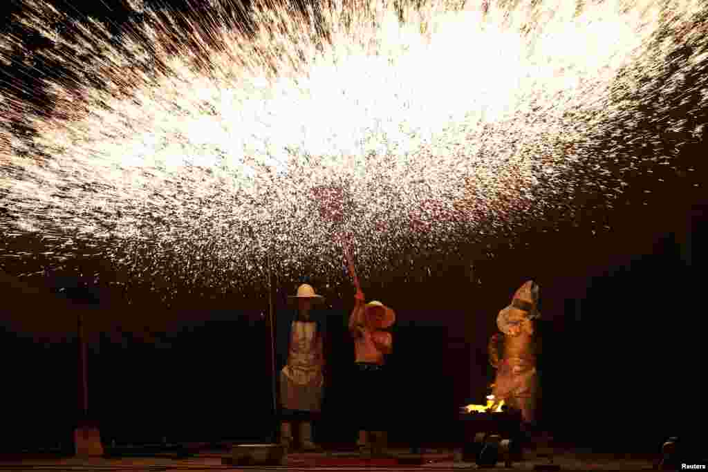 Folk artists create sparks with molten iron during a performance in Hengnan county, Hunan province, China, July 17, 2019.