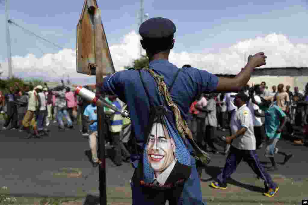 A police officer with a bag depicting the image of US President Barack Obama, on patrol as protesters march through the Musaga district of Bujumbura in Burundi.