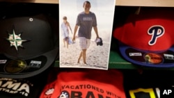 A photograph of President Barack Obama, top, is attached to a shelf near hats and souvenir clothing in a shop, Aug. 6, 2015, in Oak Bluffs, Mass., on the island of Martha's Vineyard. 
