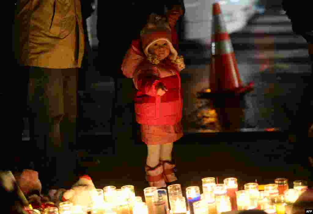 2012年12月16日，人们在一处临时纪念龛凭吊小学枪击案遇难者，一名小孩手指着蜡烛。