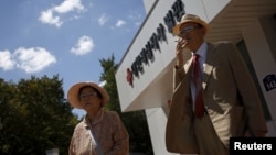 Oh Seong-ik (R), 83, who said he has family members living in North Korea, smokes after preparing documents for reunion, outside the Red Cross building in Seoul, South Korea, September 7, 2015. 