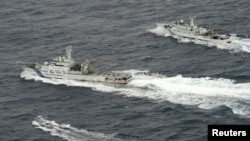 An aerial photo shows Chinese marine surveillance ship Haijian No. 66 (top) trying to approach a Japanese fishing boat (bottom) as Japan Coast Guard vessel Ishigaki cruises next to the Chinese ship, in the East China Sea. (Reuters)