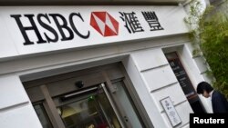 FILE - A worker uses an ATM at a branch of HSBC.