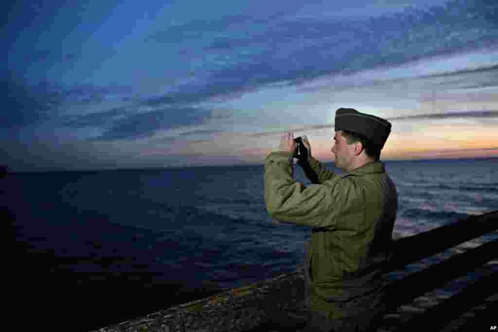 A military enthusiast takes a snapshot of Omaha Beach, France, June 6, 2014.