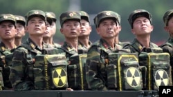 北韓士兵在2013年一次閱兵儀式中展示核武器標誌。(美聯社)