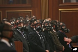 Security forces wear gas masks at the Kosovo assembly, after opposition lawmakers released tear gas canisters disrupting a parliamentary session in Kosovo's capital Pristina, Feb. 26, 2016.