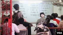 A student is reading and translating English words in a pay-per-lesson English class on the southeast corner of Baktouk High School in Phnom Penh, Cambodia, at around 6 PM on July 17, 2015. (Sou Pisen/VOA Khmer)