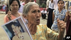 A supporter of Burmese pro-democracy leader Aung San Suu Kyi holds her portrait as she talks to journalists,12 Nov. 2010.