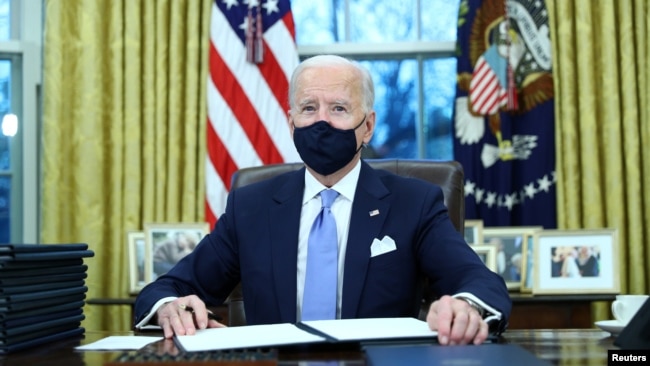 Tổng thống Mỹ Joe Biden kí các sắc lệnh hành pháp trong Phòng Bầu dục của Nhà Trắng ở Washington, sau khi ông nhậm chức tổng thống thứ 46 của Hoa Kỳ, ngày 20 tháng 1, 2021.