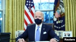 U.S. President Joe Biden signs executive orders in the Oval Office of the White House in Washington, after his inauguration as the 46th President of the United States, U.S., January 20, 2021.