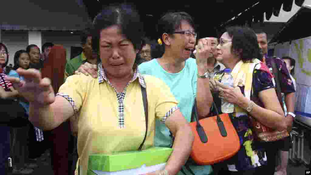 Familiares dos passageiros do AirAsia 8501 choram à saída do centro de crise instalado no Aeroporto Internacional de Juanda International em Surabaya, Java, Indonésia. O avião da Air Asia caiu a 28 de Dezembro. Indonésia Dez. 31, 2014.