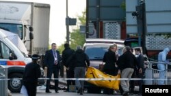 Police officers carry equipment while investigating a crime scene where one man was killed in Woolwich, southeast London May 22, 2013.