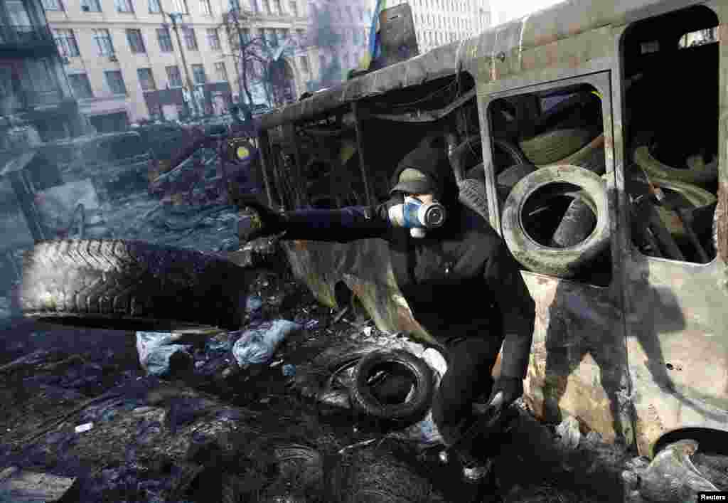 Một người biểu tình chống chính phủ ném chiếc vỏ xe về phía đang xảy ra xô xát với cảnh sát chống bạo động trong thủ đô Kyiv, 26/1/14