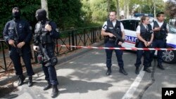 French hooded police officers guard the area with other police officers after a knife attack Aug. 23, 2018 in Trappes, west of Paris.