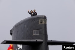 FILE - Taiwan President Tsai Ing-wen waves as she boards Hai Lung-class submarine (SS-794) during her visit to a navy base in Kaohsiung, Taiwan, March 21, 2017.