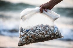 Julian Mercer memegang plastik berisi puntung rokok yang dipulungnya dari pantai Laut Tengah sebagai bagian kampanye lingkungan hidup di pantai di Tel Aviv, Israel, 20 April 2021. (Foto: Amir Cohen/Reuters)