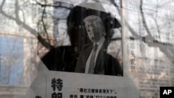 FILE - A man reading a newspaper posted on a public newspaper bulletin board is reflected on a glass as a photo of U.S. President-elect Donald Trump is published on a Chinese newspaper with an article that reads "Trump uses fist to talk" in Beijing, Jan.