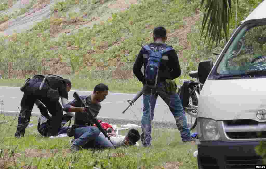 Police search two men who came out of Tanjung Labian, a village near where Malaysian troops stormed the camp of an armed Philippine group, March 6, 2013.