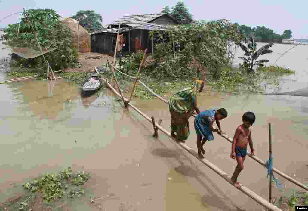 Warga menggunakan jembatan bambu untuk berpindah ke lokasi lain akibat banjir melanda distrik Morigaon, negara bagian Assam, India.&nbsp;