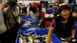 A woman buys fish at the Villa Maria del Triunfo fish market in Lima, Peru. (File)