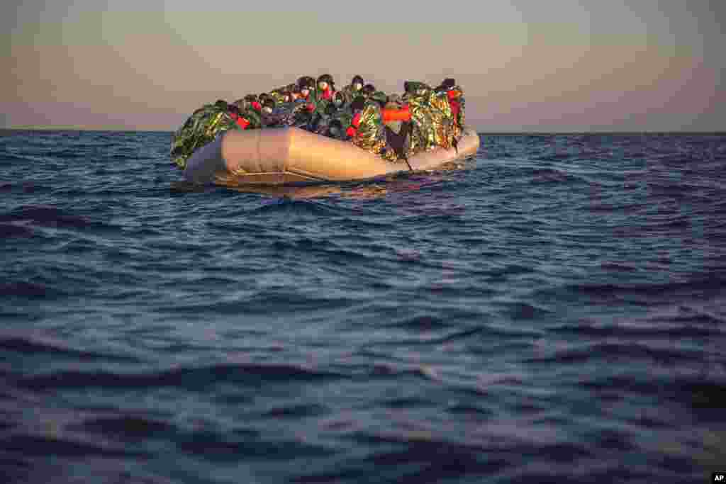 African migrants and refugees wait on an overcrowded rubber boat, as aid workers of the Spanish NGO Open Arms approach them in the Mediterranean Sea, international waters, off the Libyan coast, Feb. 6, 2021.